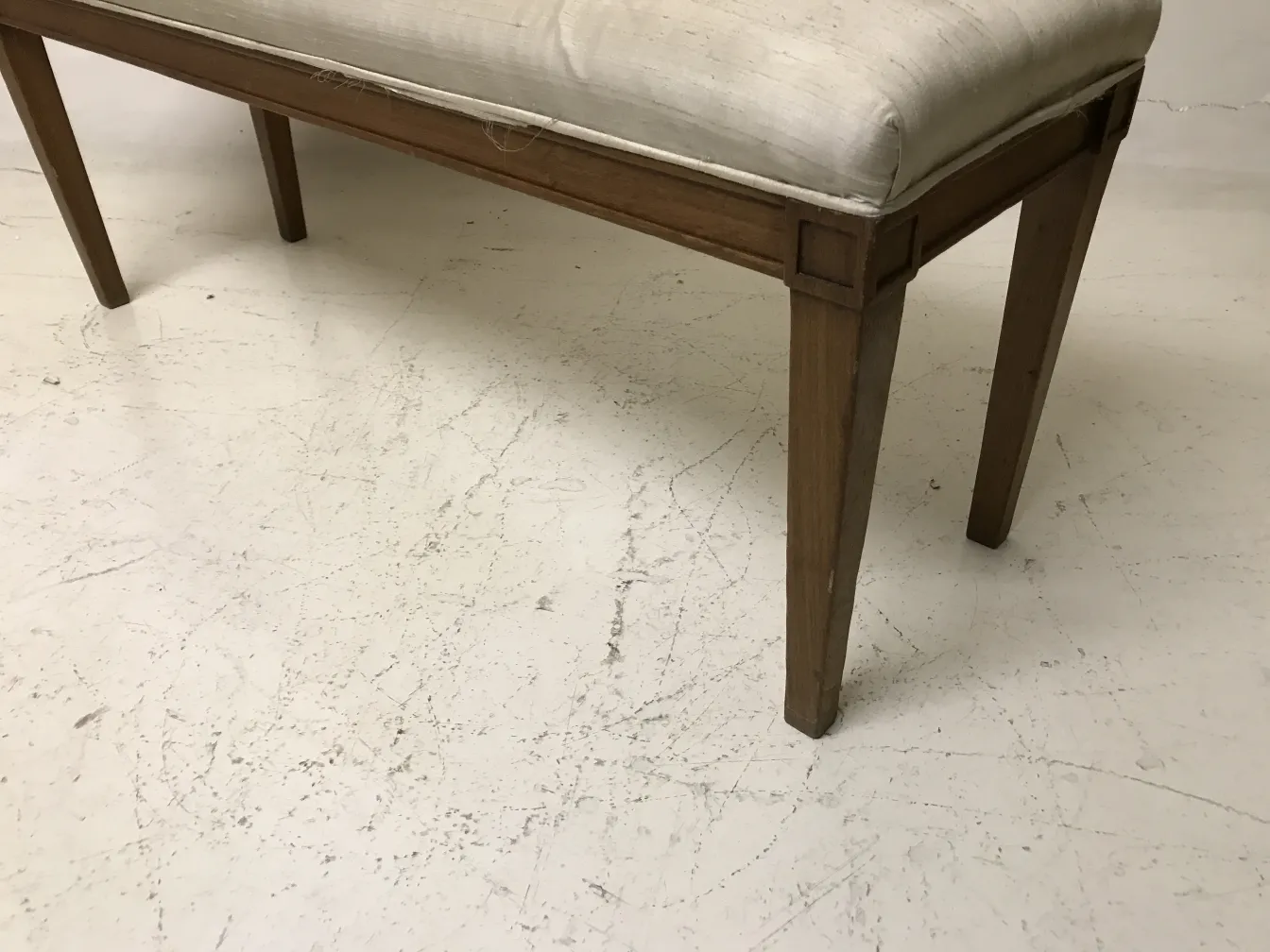 Tabouret ancien au design simple et assise blanche, sur fond clair et propre.