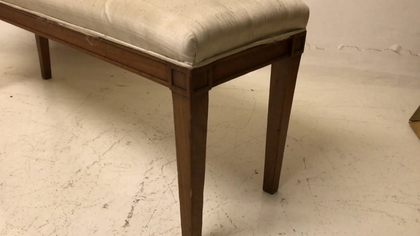 banqueta antiga com um design simples e almofada confortável, em um ambiente neutro