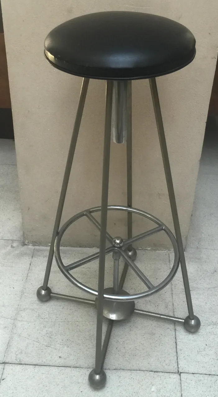 Tabouret ancien avec assise noire et base métallique dans un cadre moderne.