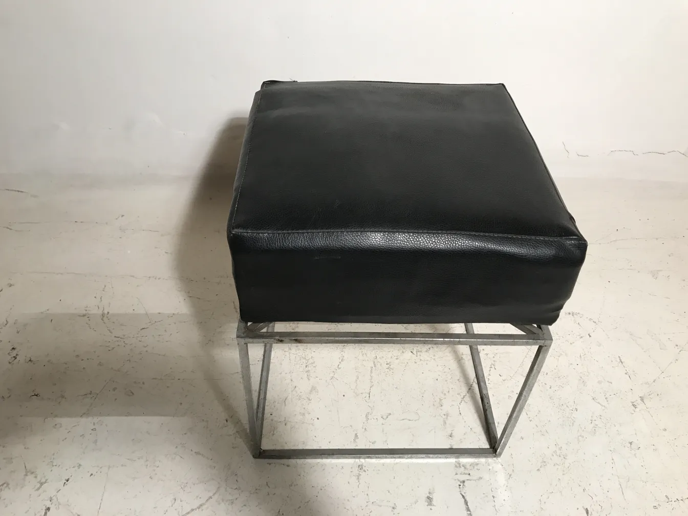 black antique stool with metal base, on light background