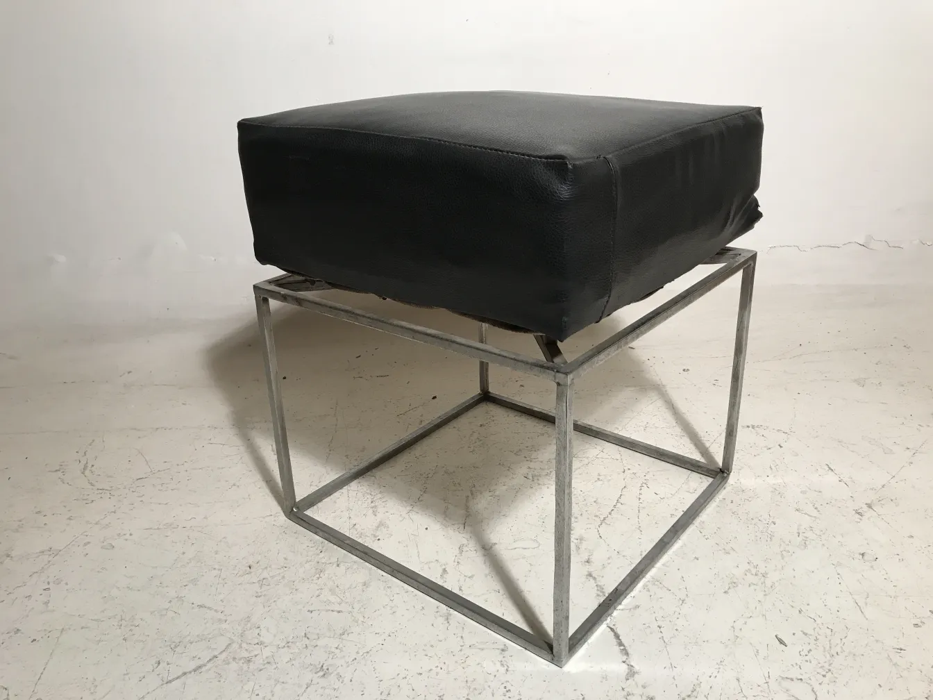 Antiga banqueta com assento preto em um ambiente neutro.