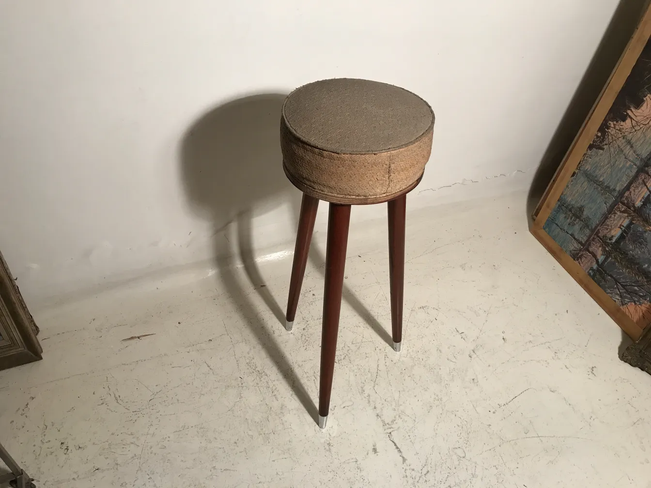 banqueta antigua de tres patas en un entorno minimalista