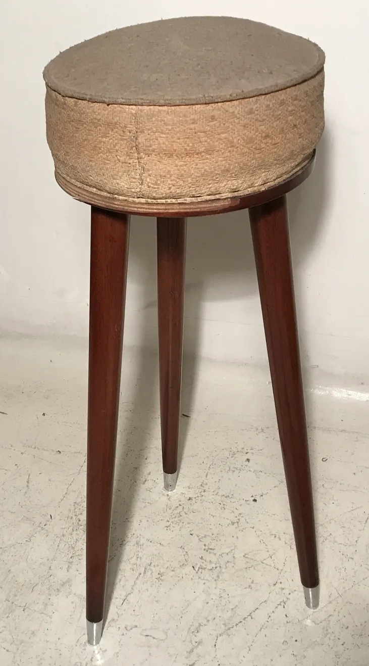 Antique stool with elegant legs against a neutral background