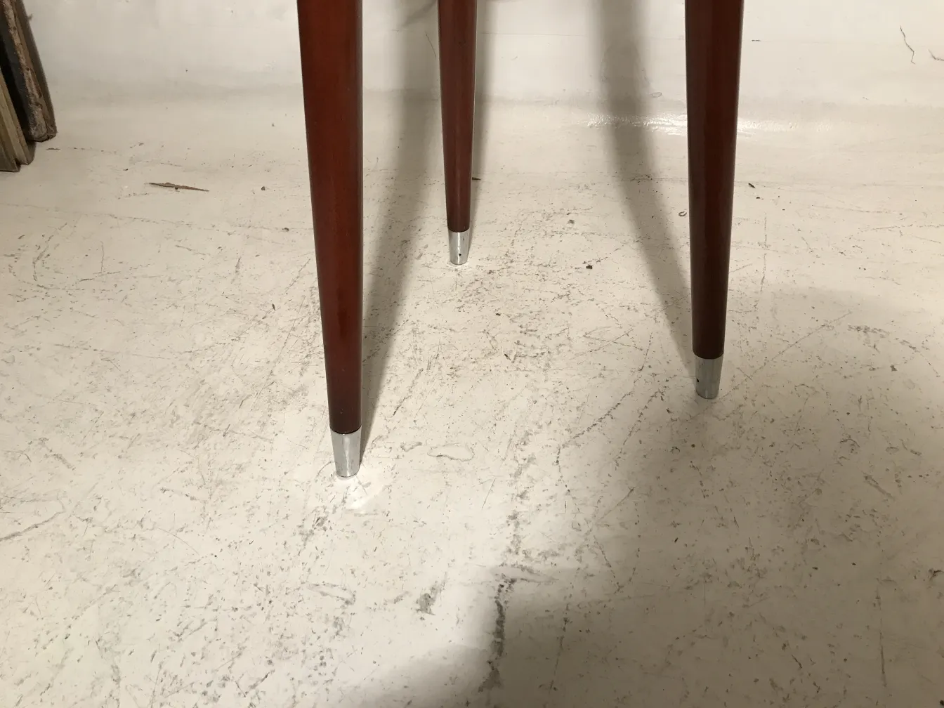 Antiga banqueta com pernas finas, fundo neutro.