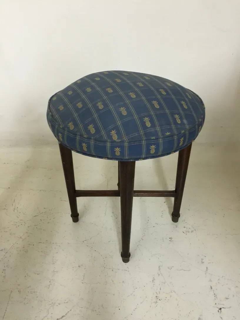 Tabouret ancien avec coussin bleu décoré, fond neutre.