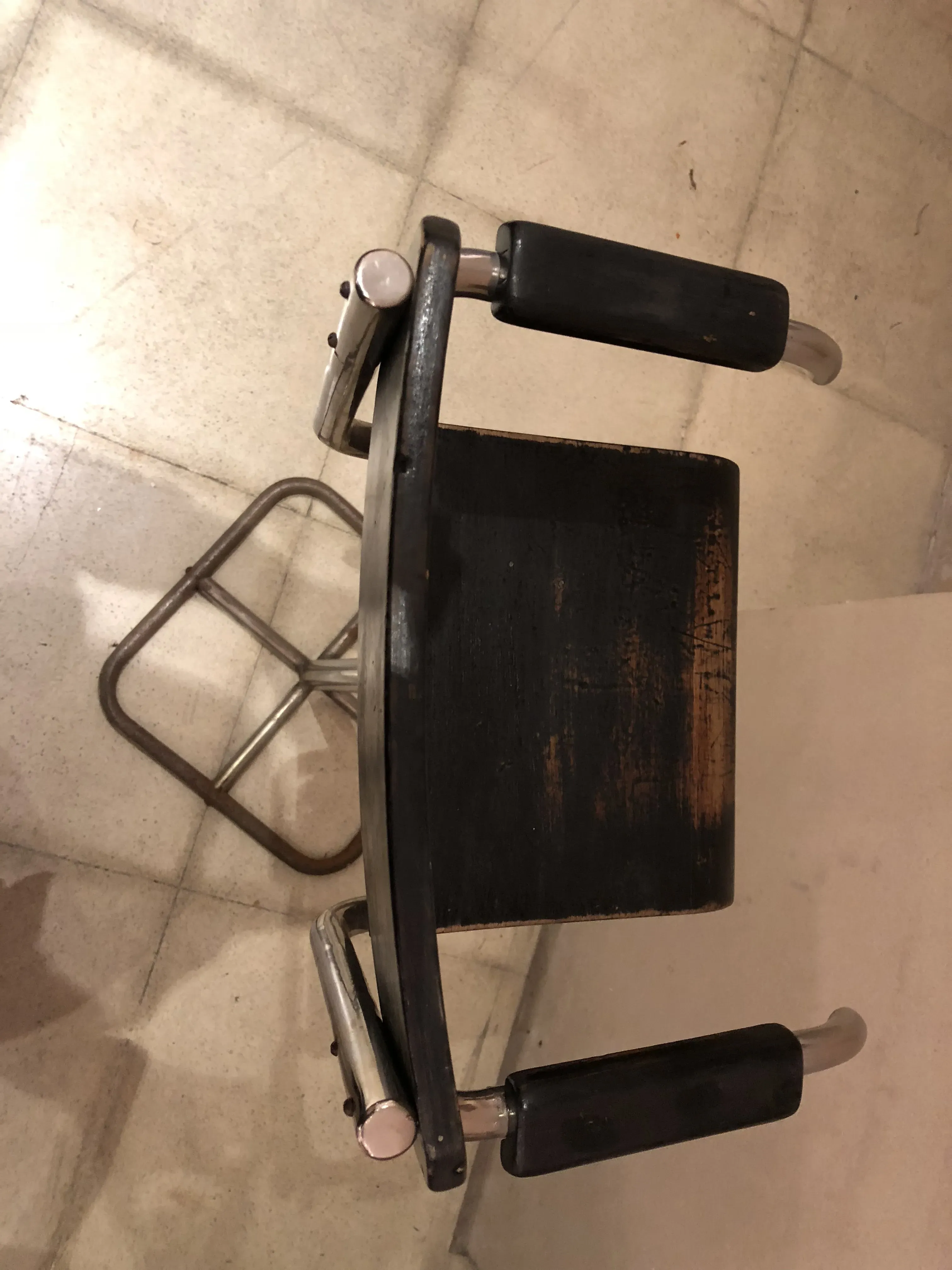 Vue de dessus d'une chaise enfant ancienne avec accoudoirs dans un environnement neutre.