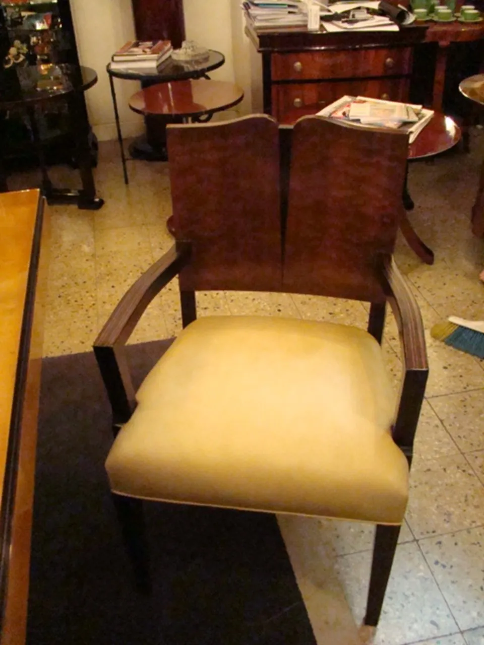 Poltrona antica in stile Art Deco con bracci e cuscino chiaro in un ambiente elegante.