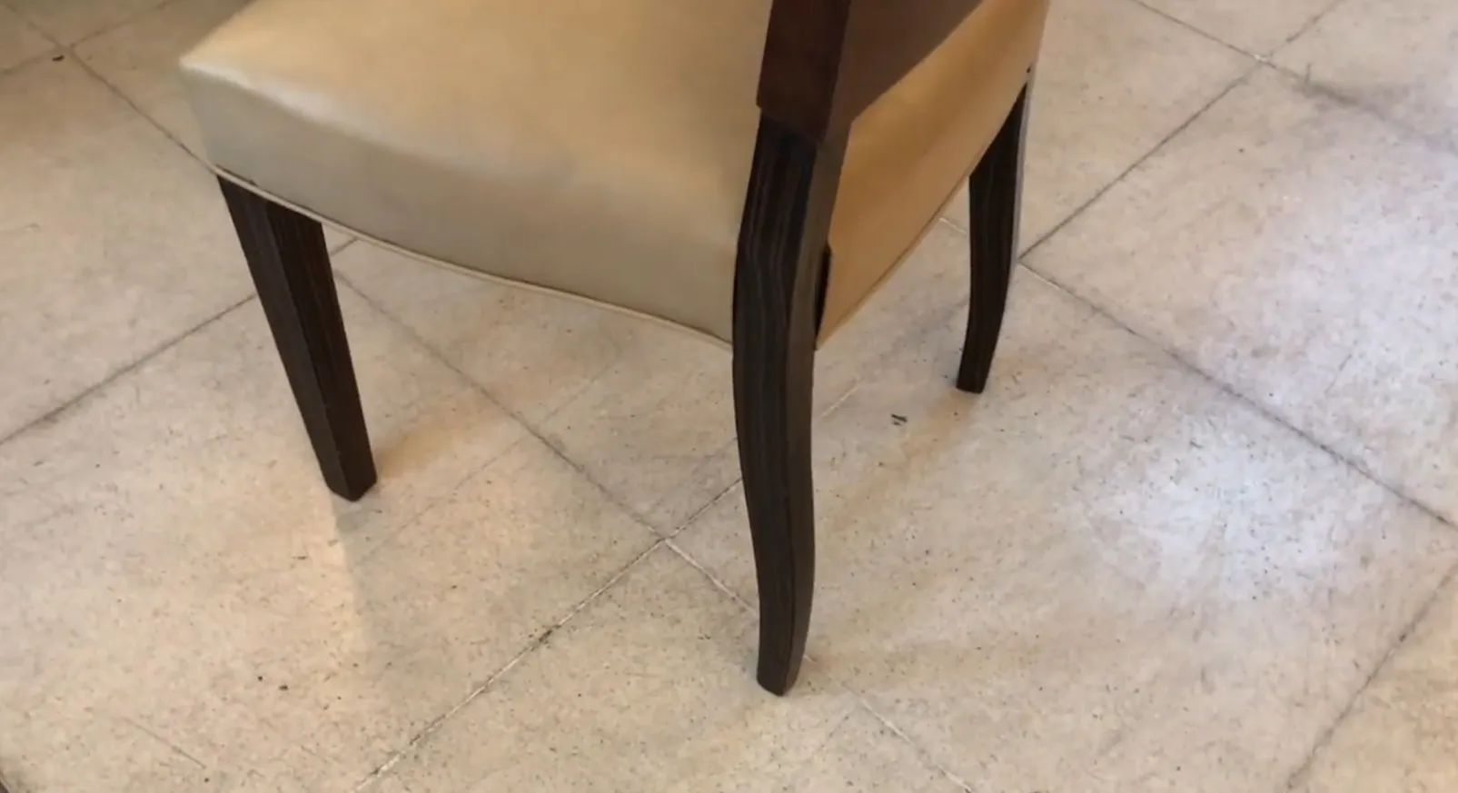 Détail d'une chaise ancienne avec des pieds élégants dans un environnement sobre.