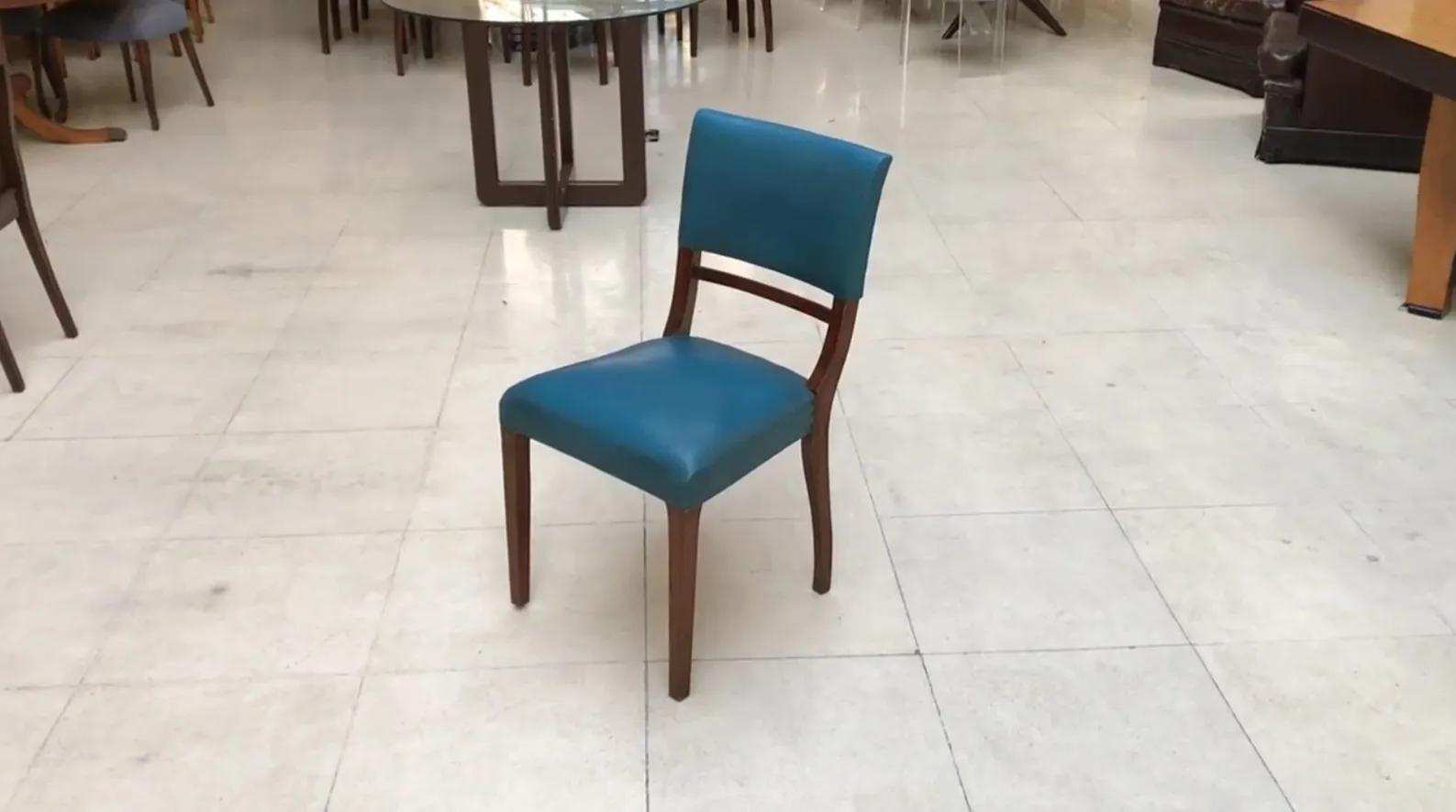 6 antike Stühle in verschiedenen Farben in einem hellen Raum.