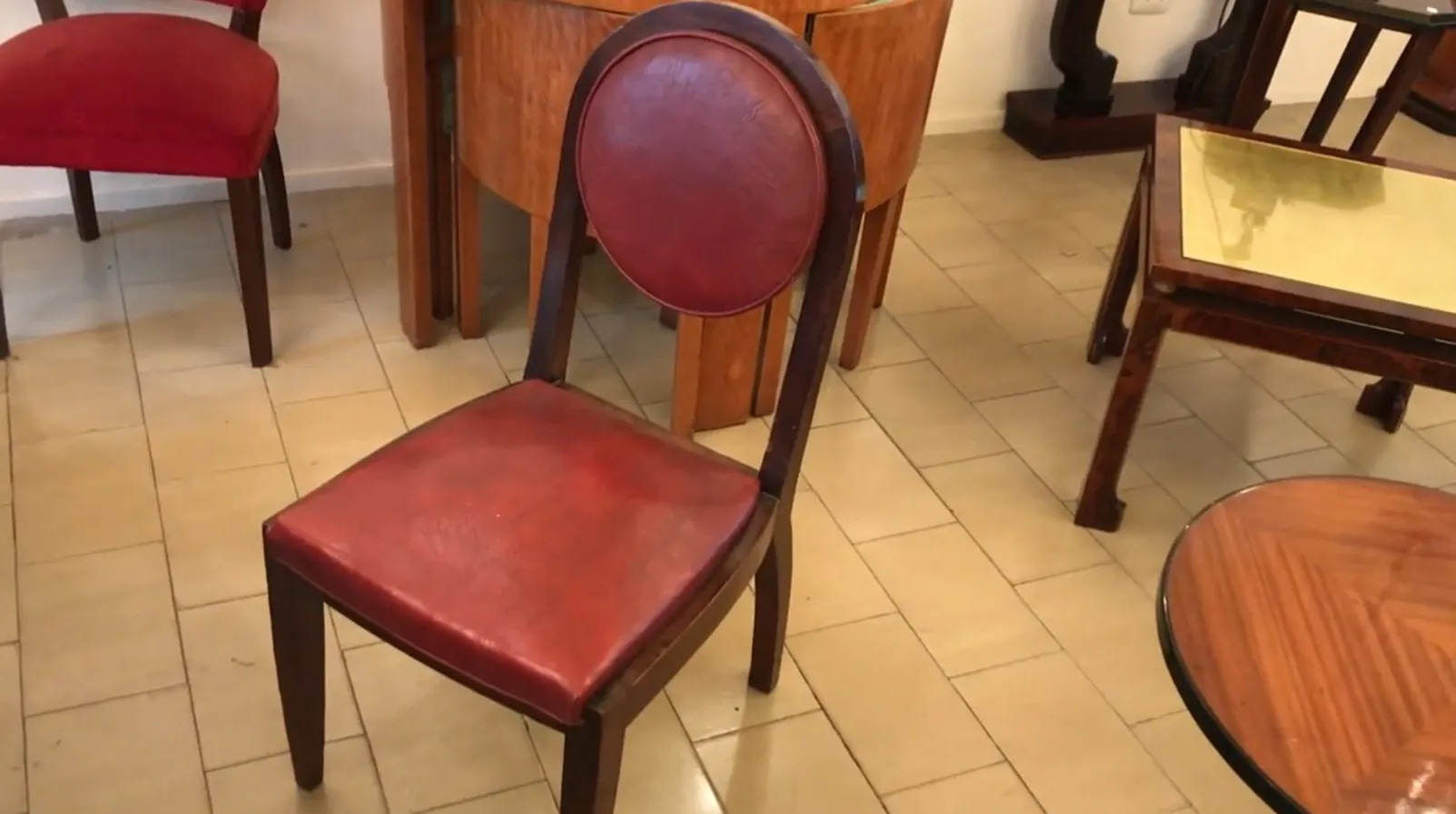 12 chaises anciennes à restaurer, avec des sièges rouges, dans un cadre chaleureux.