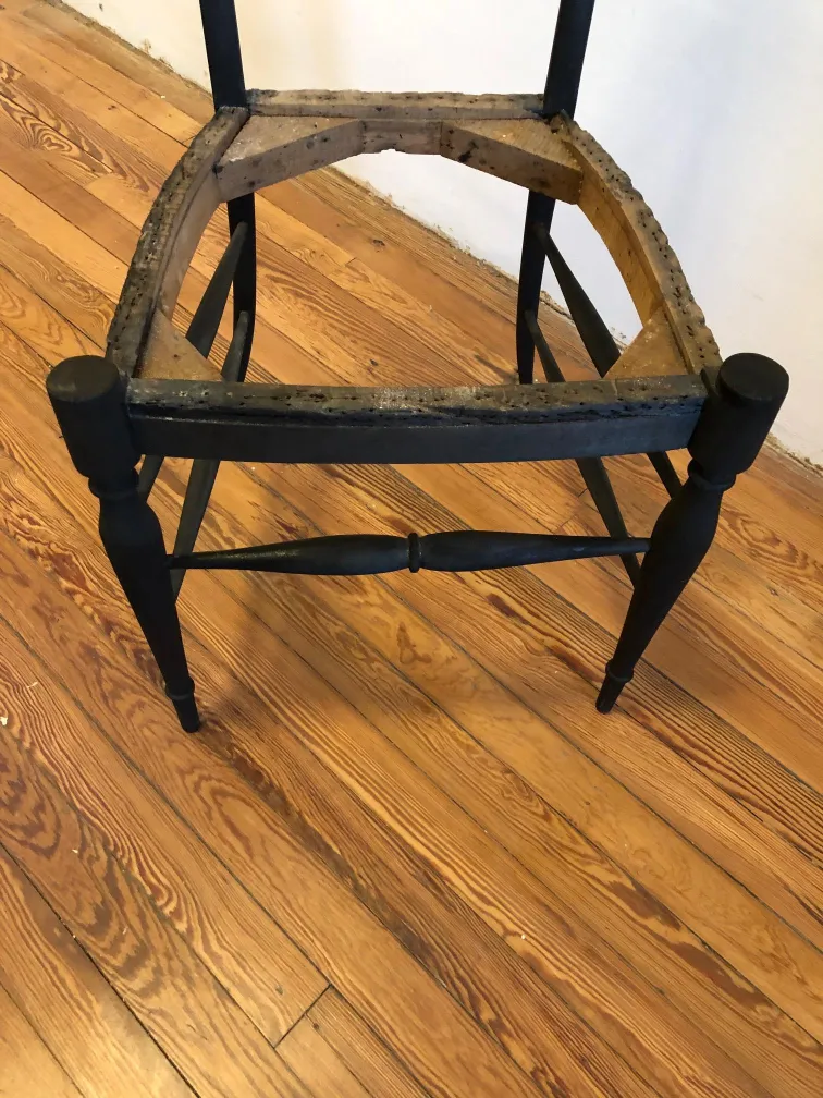View of 10 antique chairs with damaged structure in a light setting.