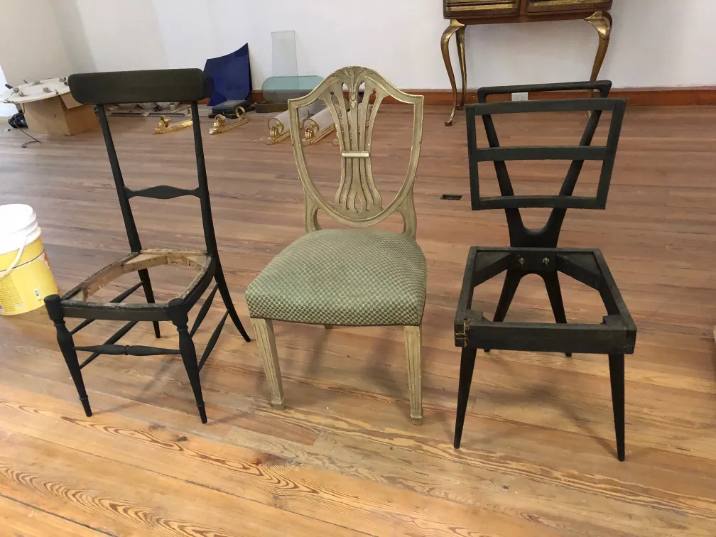 Three antique chairs in restoration process, various styles, clear environment.