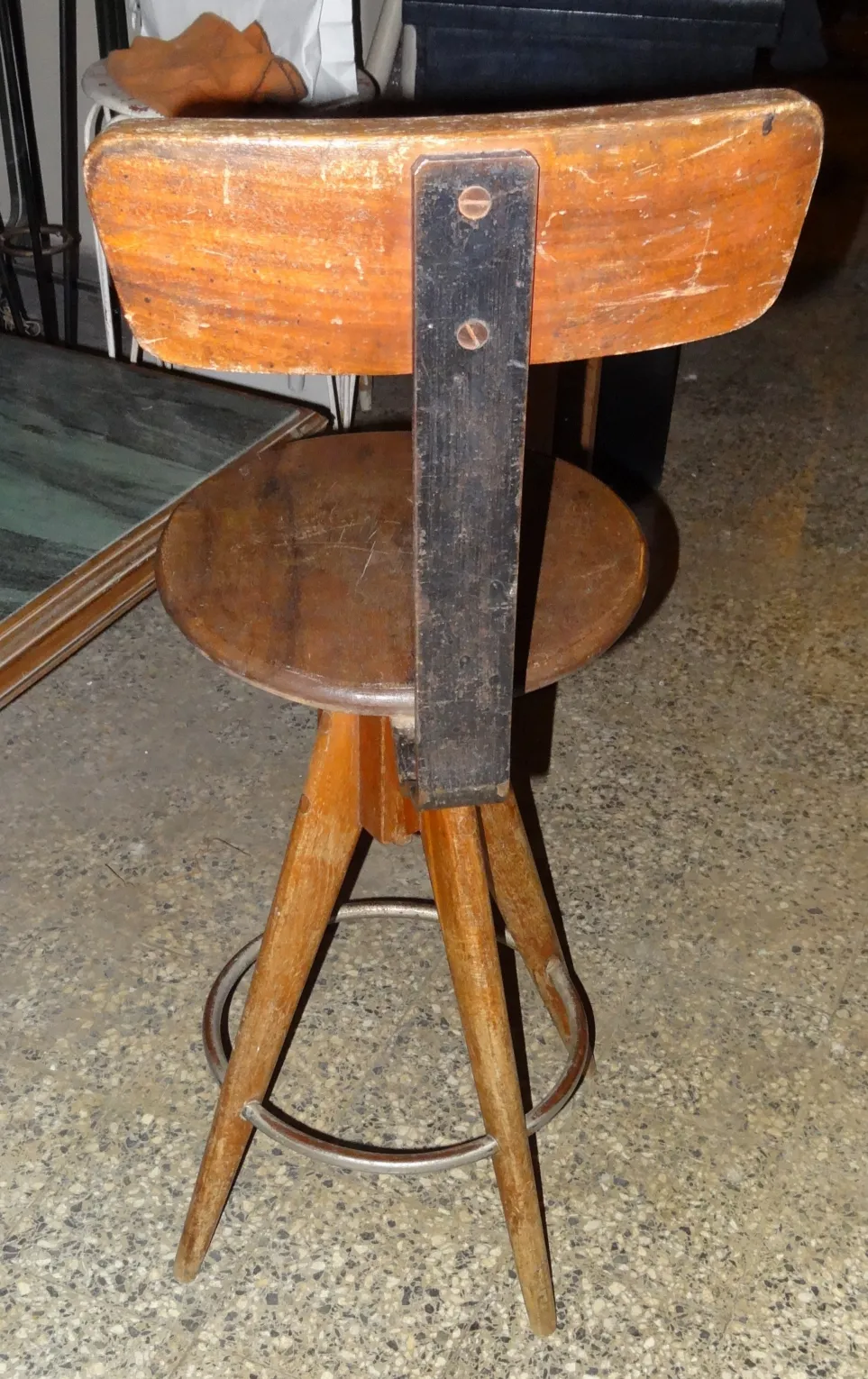 Tabouret ancien en bois avec dossier dans un environnement vintage.