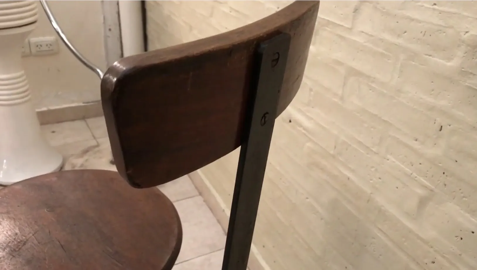 Vintage wooden stool with backrest in a simple setting.