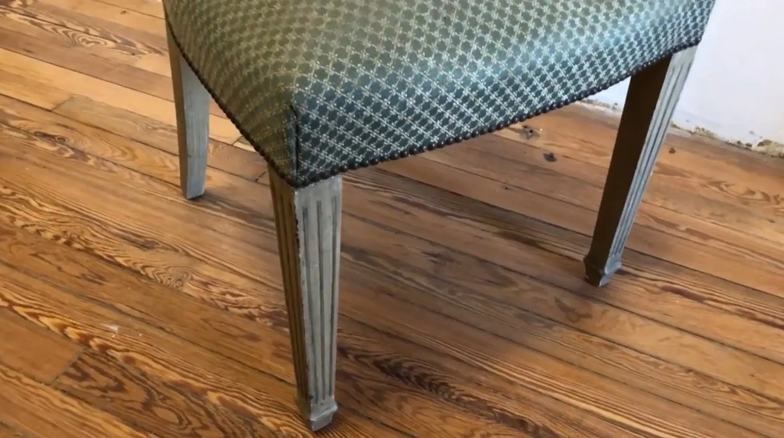 Detail of an antique maison jansen chair to restore with elegant legs and unique upholstery in a cozy environment.