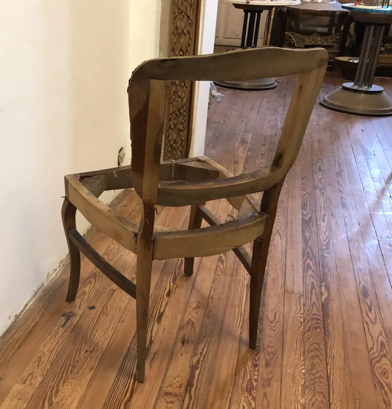 Side view of 6 antique chairs partially restored in a wooden floor environment.