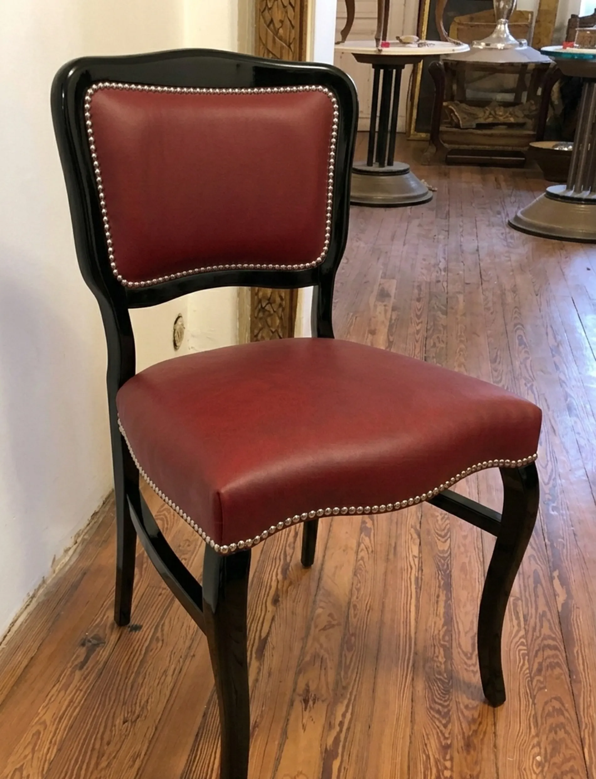 View of an antique chair with curved backrest and red upholstery in a classic setting.