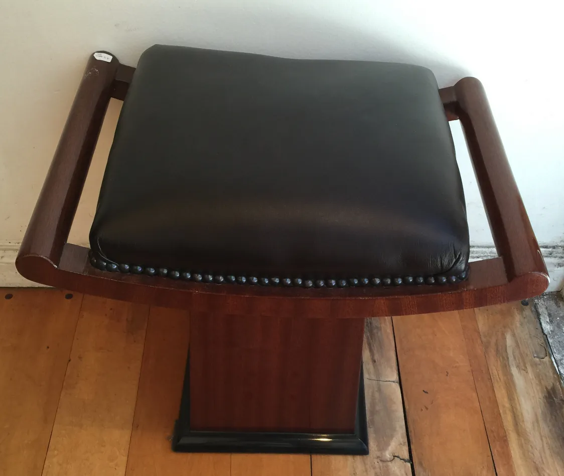 Tabouret ancien en bois avec assise noire et bras, détail élégant.