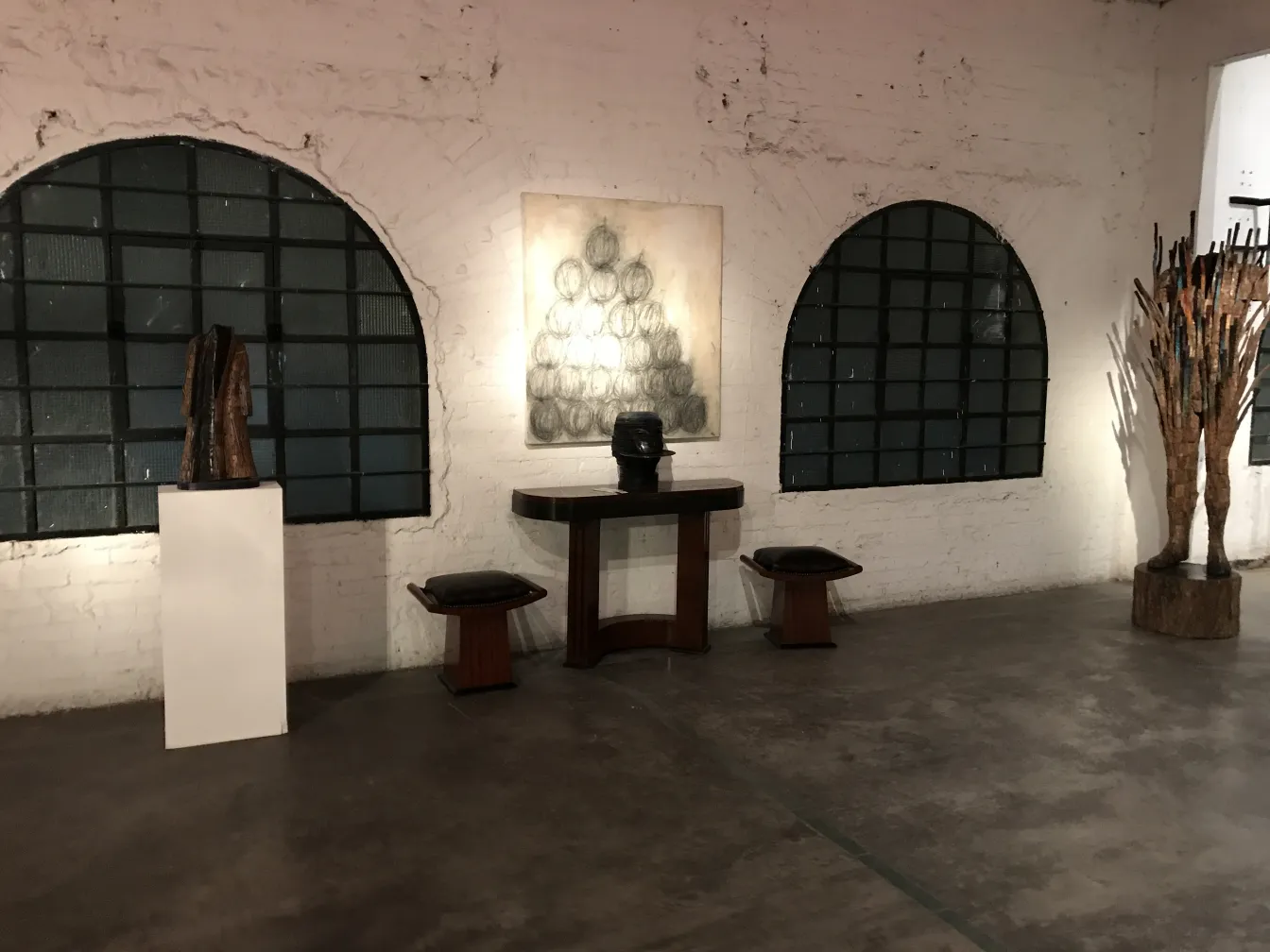 Dos banquetas en una galería de arte con obras y esculturas.