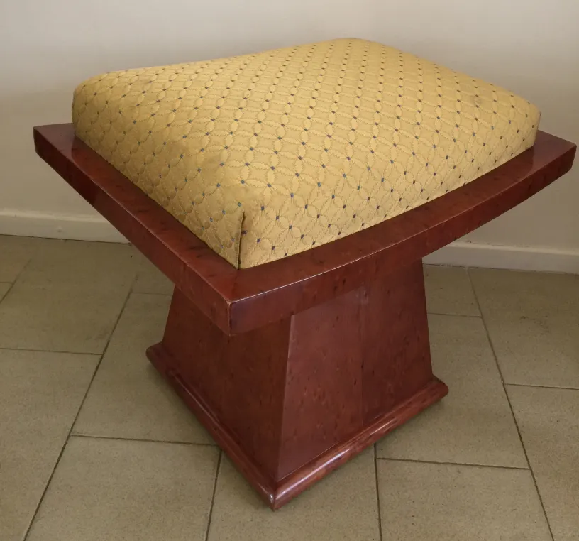 Tabouret avec coussin jaune sur une base carrée, fond neutre.