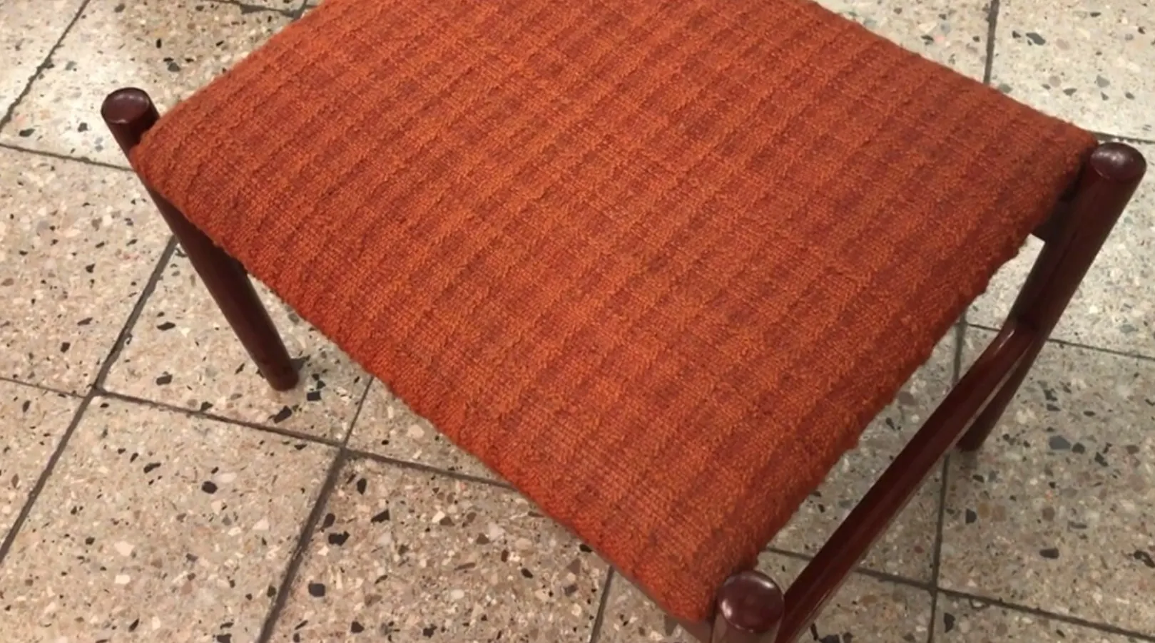 Banqueta antiga laranja sobre piso de cerâmica