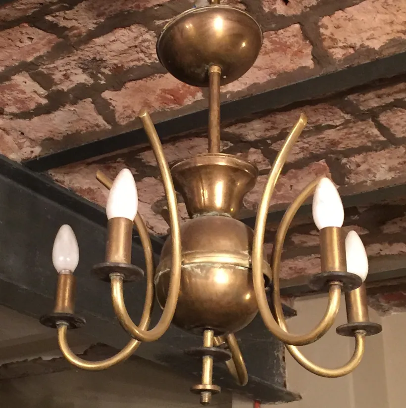 lámpara de techo antigua Art Deco con brazos curvos y bombillas blancas en un ambiente acogedor