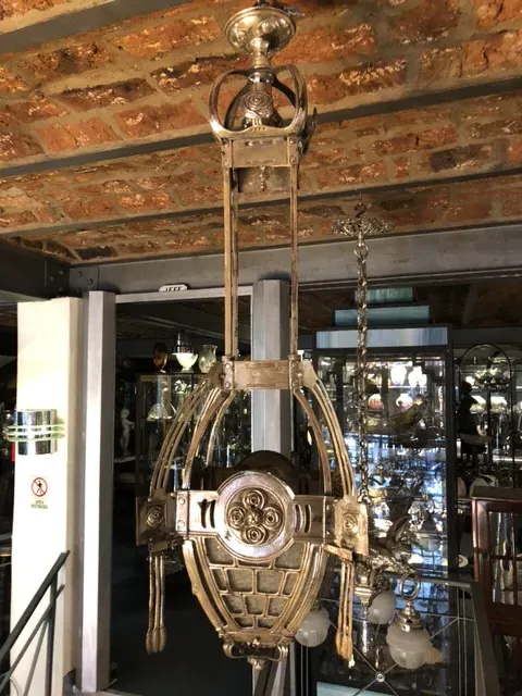 Lámpara de techo antigua de estilo Mackintosh, elegante y decorativa, colgando de un techo de ladrillo.