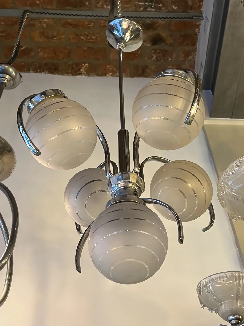 lámpara de techo antigua en estilo art deco con esferas blancas que desprenden luz en un ambiente acogedor