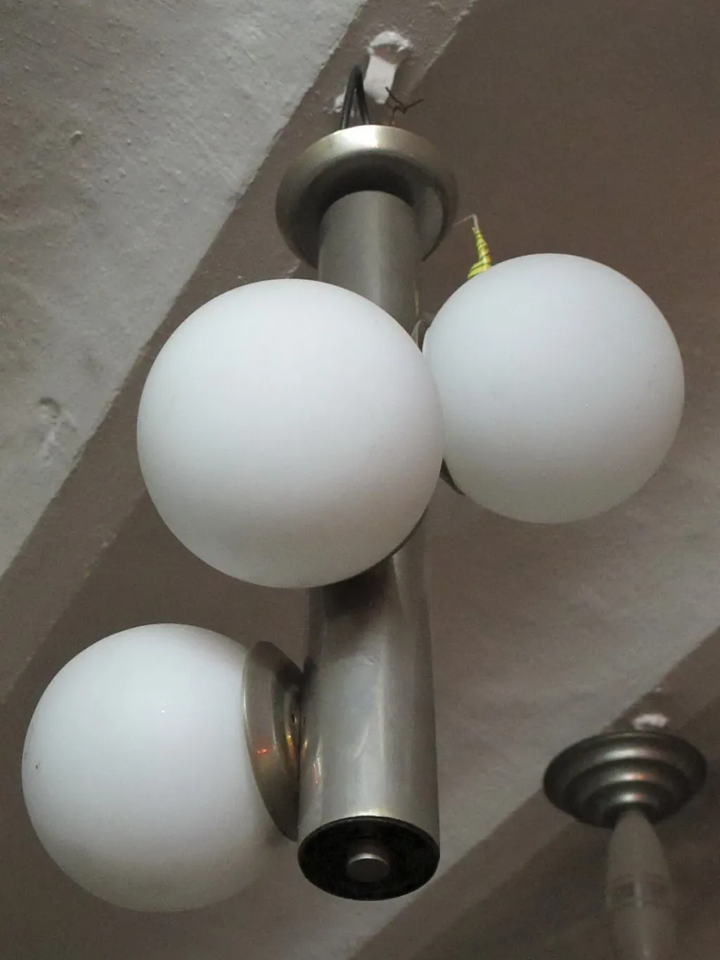 Lustre antique avec trois boules blanches, ambiance chaleureuse.