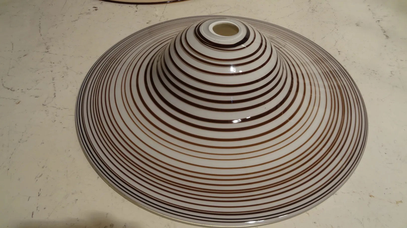 Antiga lampada de teto com desenho listrado em tons claros.