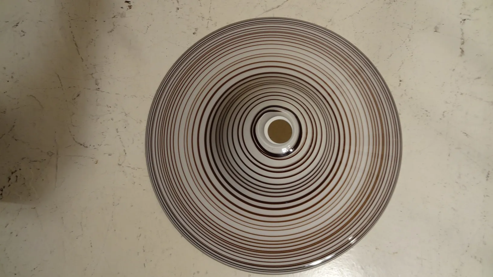 Lâmpada de teto antiga com padrões em espiral sobre fundo claro, ideal para decoração.