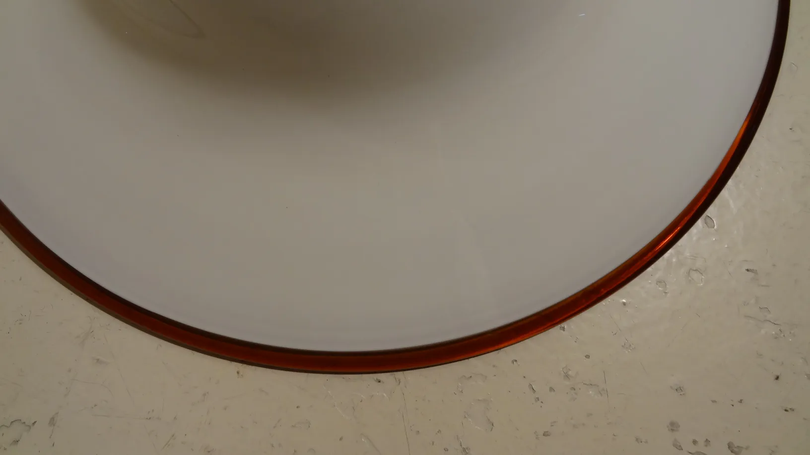 Lâmpada de teto antiga com detalhes arredondados em um ambiente simples.