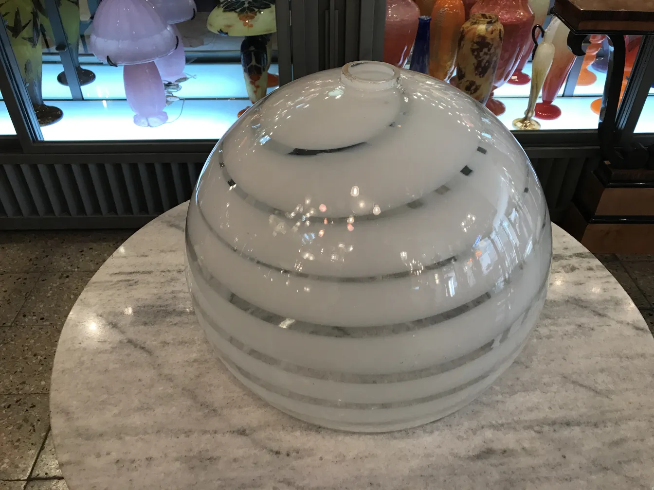 Lámpara de techo antigua con diseño esférico en un entorno elegante, luz suave.