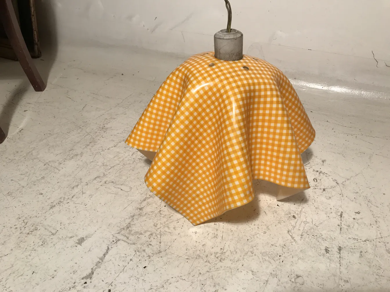 Lámpara de techo antigua con un sombrero amarillo de cuadros en un entorno vintage.