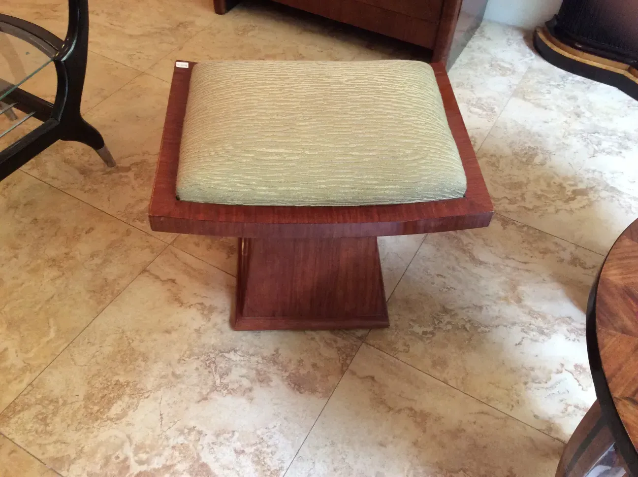 Antique stool with a soft seat in a cozy setting.