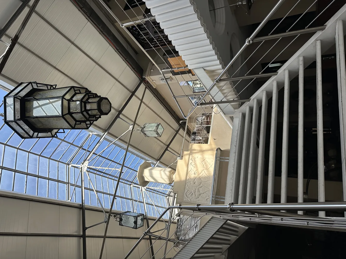 明るい廊下に吊り下げられた古いガラスランタンの画像。