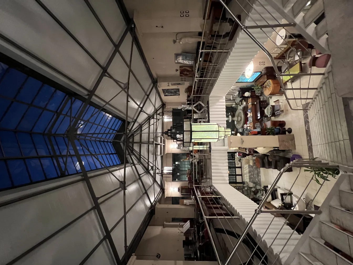 Farol antiguo de cristal en un espacio iluminado, rodeado de muebles y decoración.