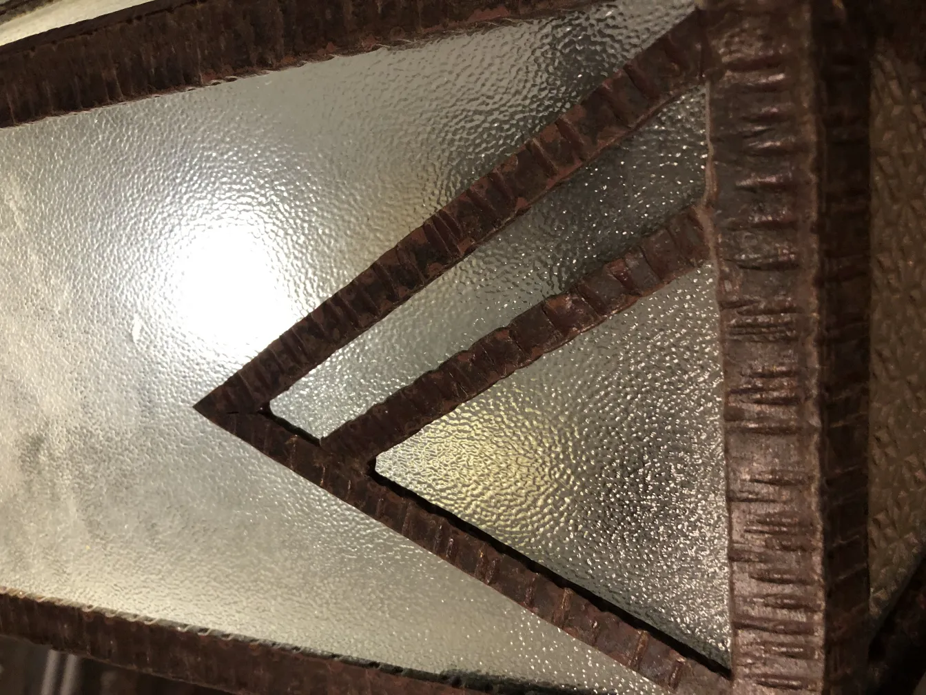 Lanterne ancienne avec verre texturé et cadre sombre.