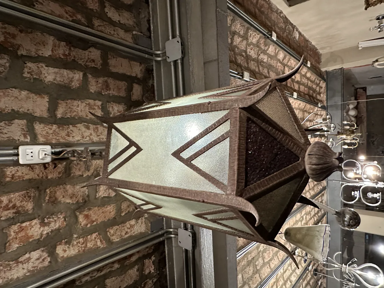 장식적인 세부 사항과 벽돌 배경을 가진 고대 유리 랜턴.