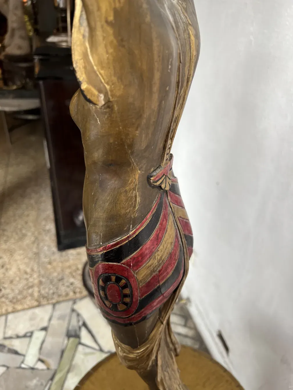 antique sculpture with decorative details in red and gold, set in a classic environment