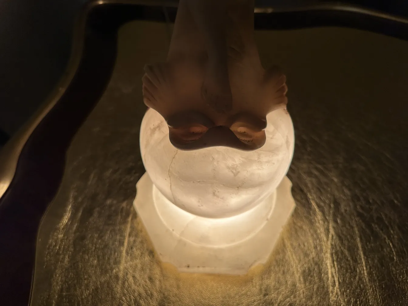 Escultura antigua de figura elegante con base iluminada