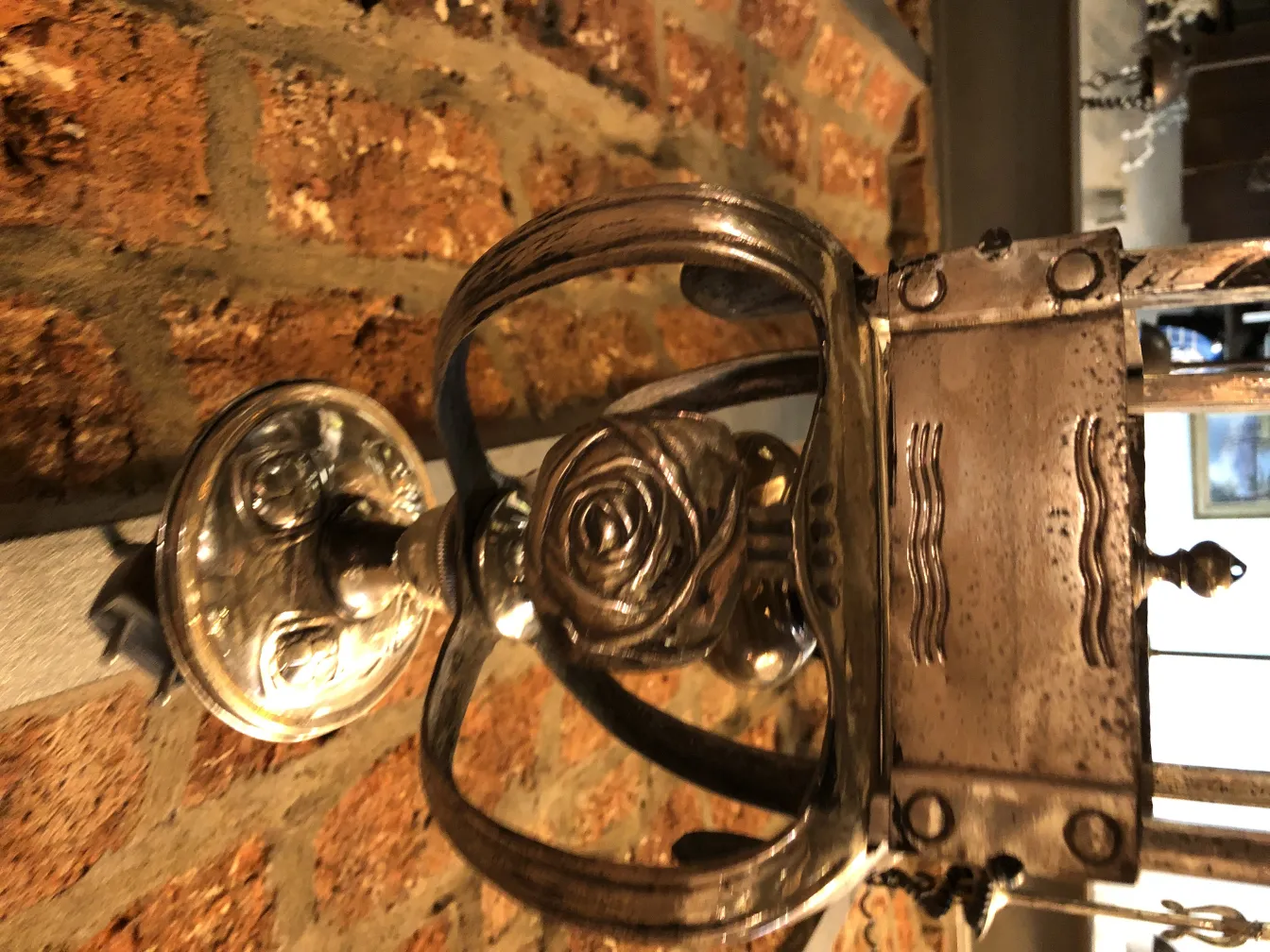 antike Lampe mit Rosenverzierungen an einer Backsteinmauer