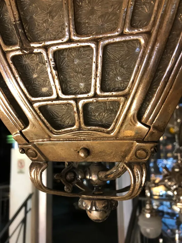 Details of an antique hanging lamp in Mackintosh style with intricate and elegant design.