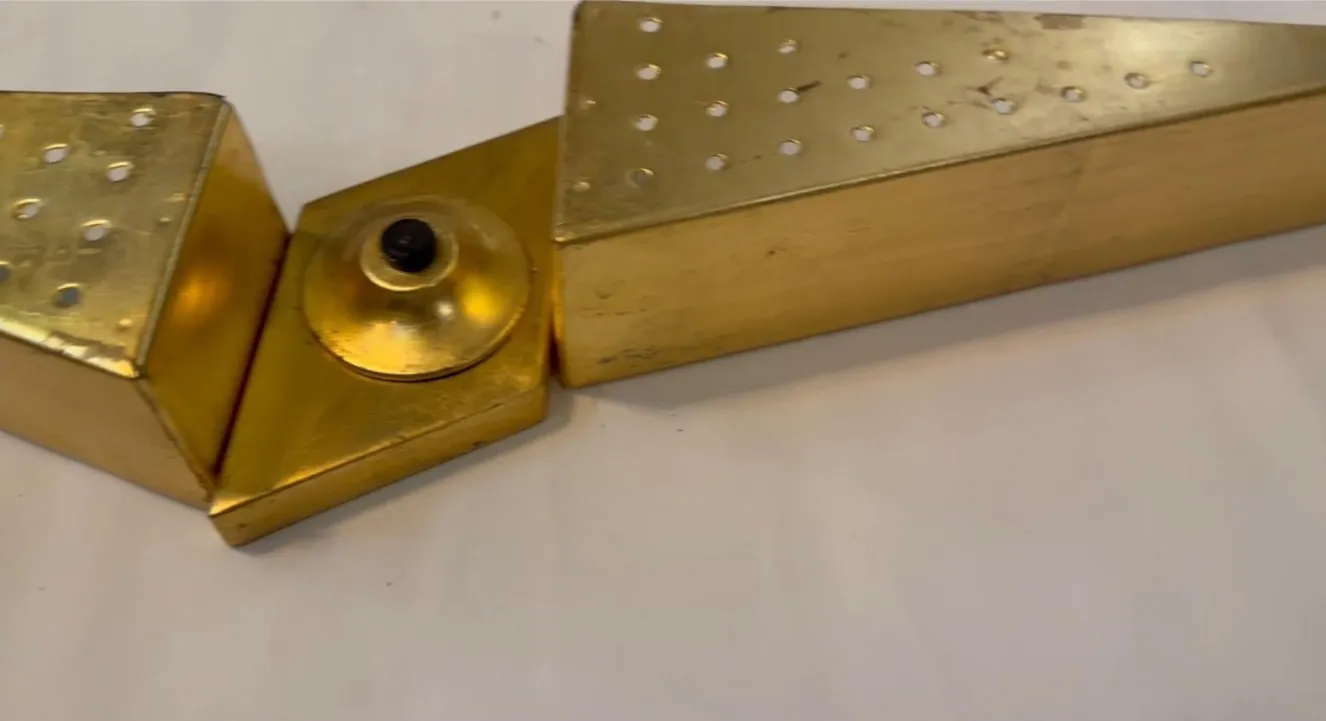 Apparecchio da parete antico con design triangolare e fori dorati.