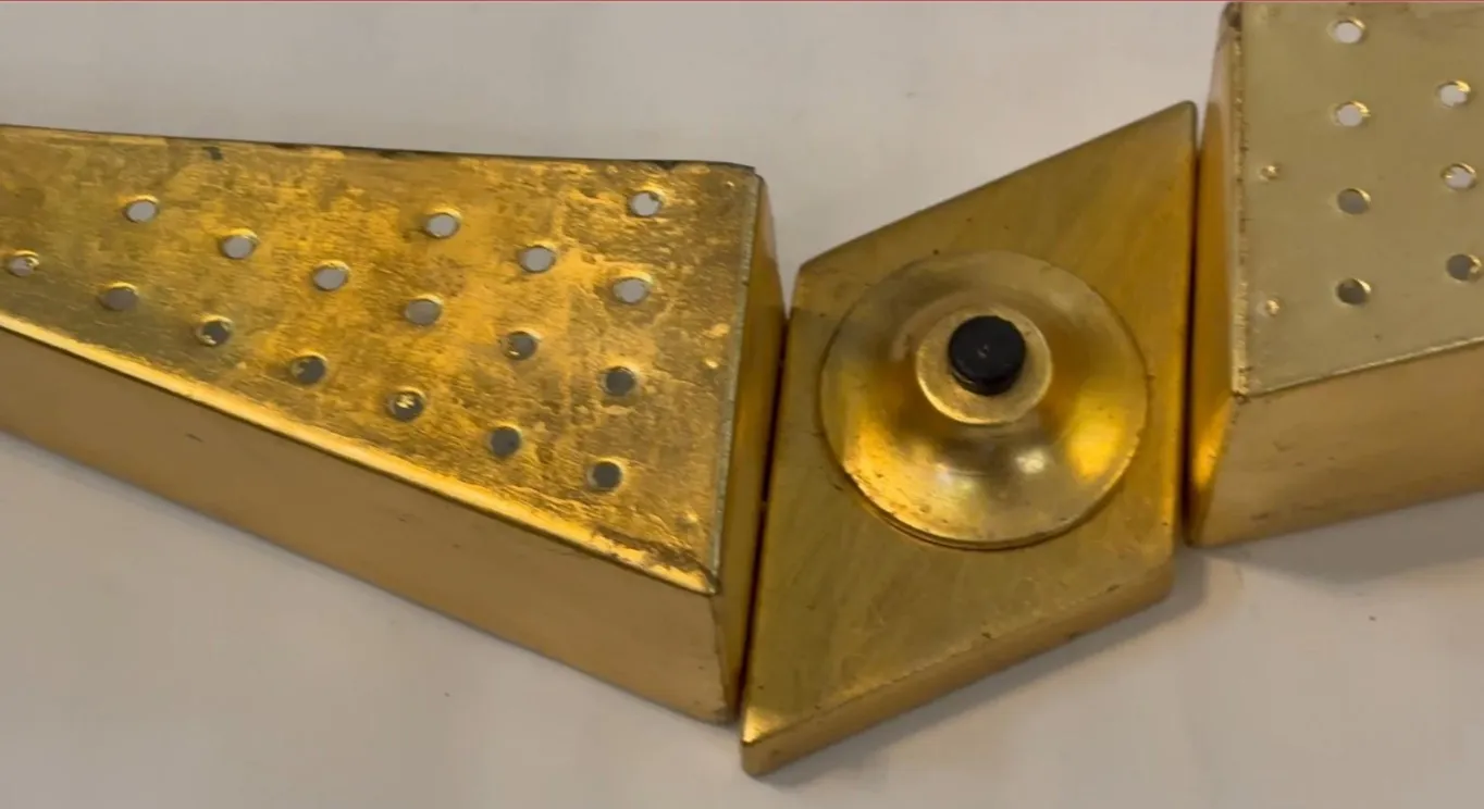 Antique sconce featuring a geometric gold design with holes.