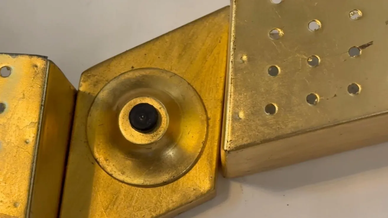 Apparecchio da parete antico con design dorato e dettagli visibili su uno sfondo chiaro.