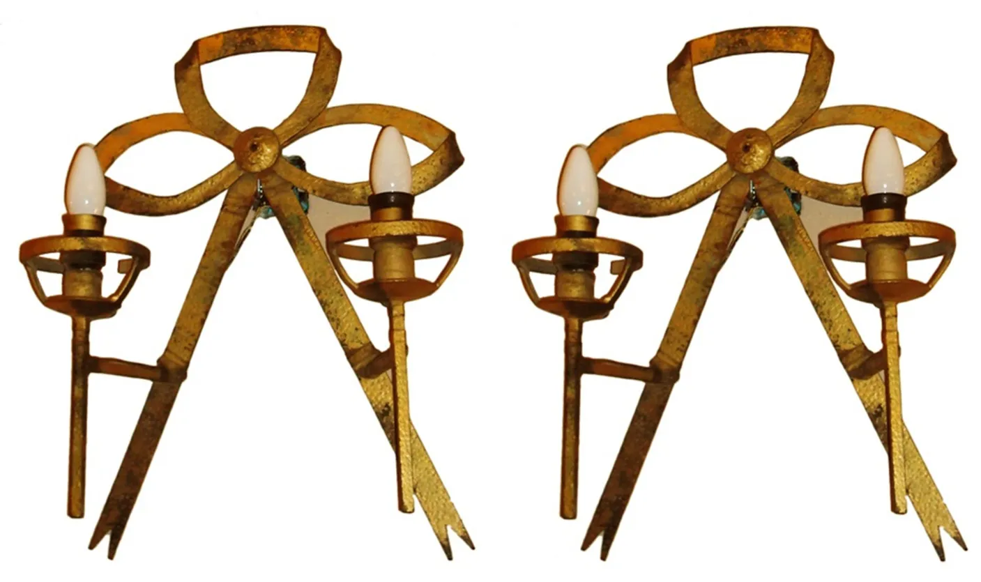 Par de apliques antiguos en forma de lazo dorado, estilo Art Deco, con bombillas de diseño ovalado.