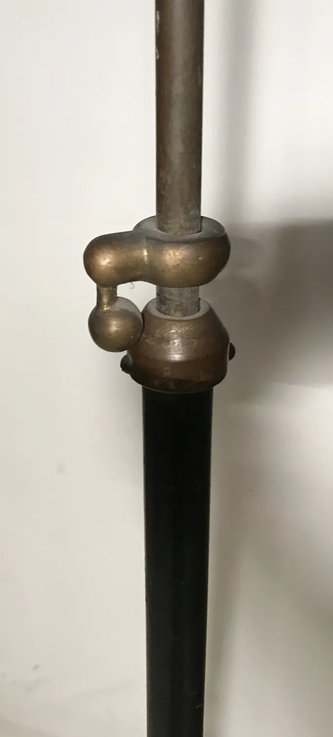 Eine antike Stehleuchte in einer gemütlichen Umgebung, mit schlichter Ornamentik.