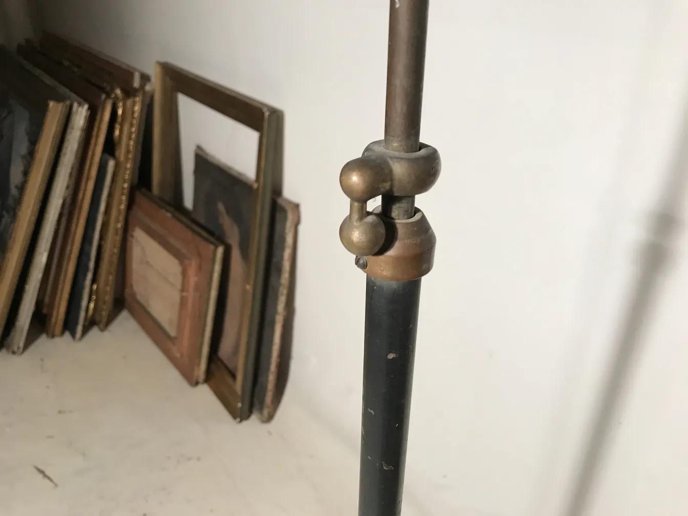 Luminária de pé antiga em estilo Art Deco com detalhes decorativos em um fundo de quadros.