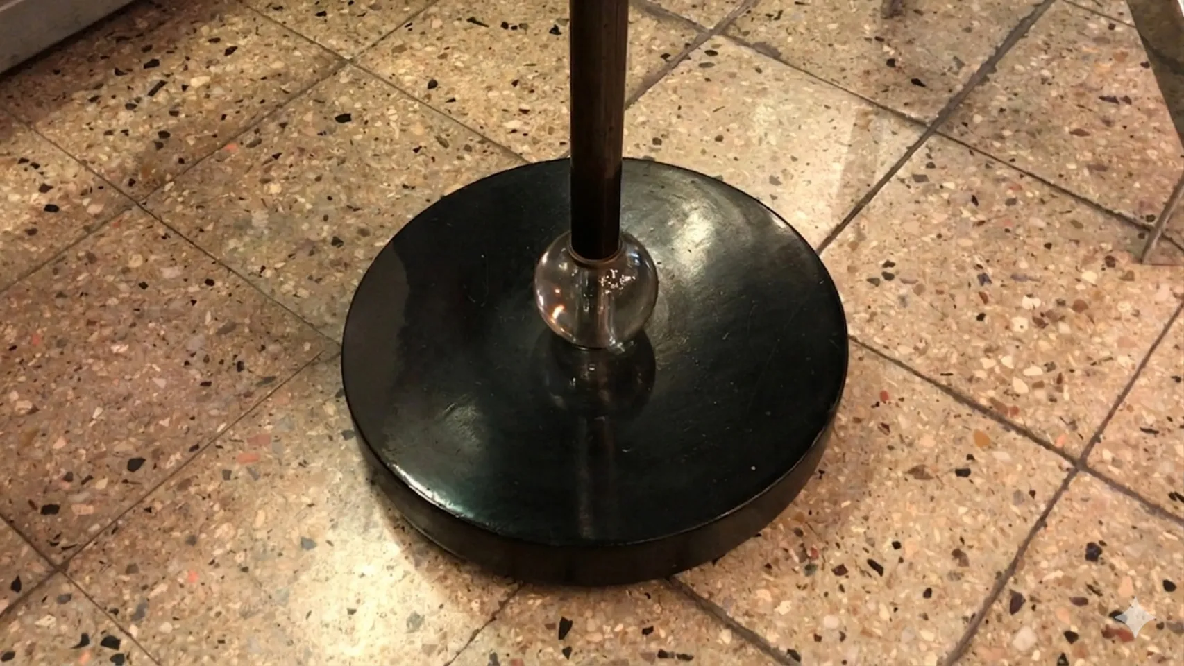 Lampada da terra antica in stile Art Deco con base nera e dettagli curvi in un ambiente elegante.